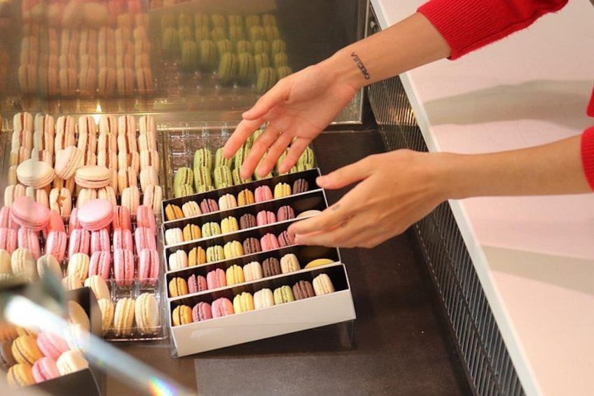 Une personne choisit des macarons dans une vitrine. 5