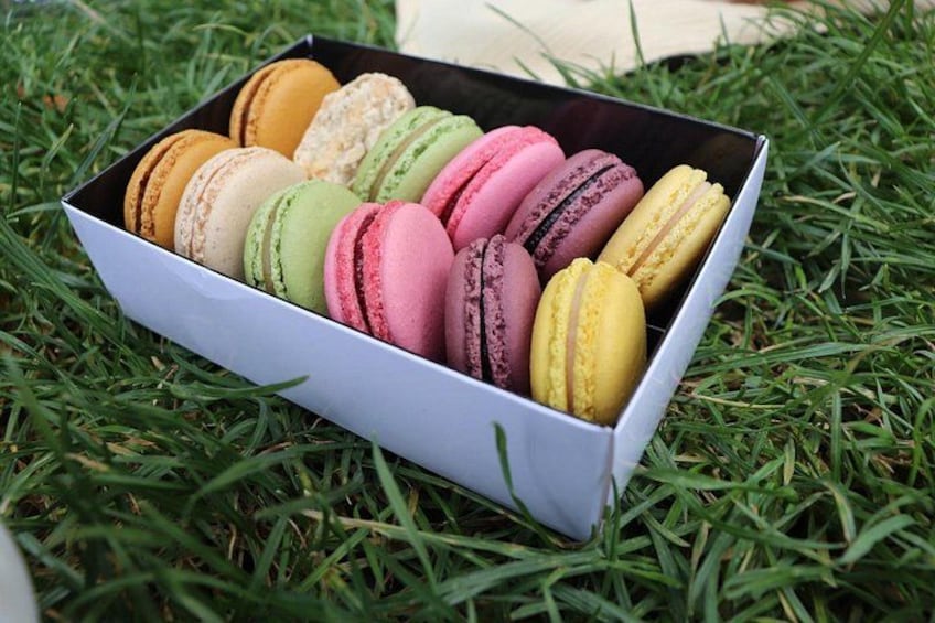 Une boîte de macarons multicolores posée sur l’herbe. 1