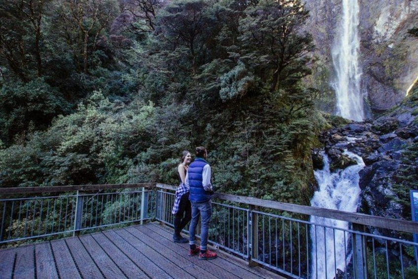 A wooden deck with a metal railing overlooking a waterfall. 5
