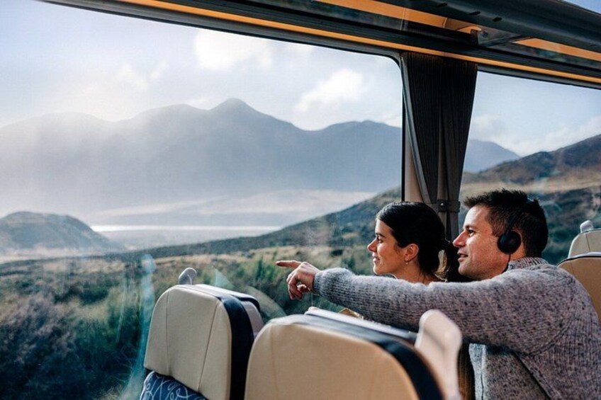 A couple seated by a window on a train, overlooking a mountainous landscape. 3