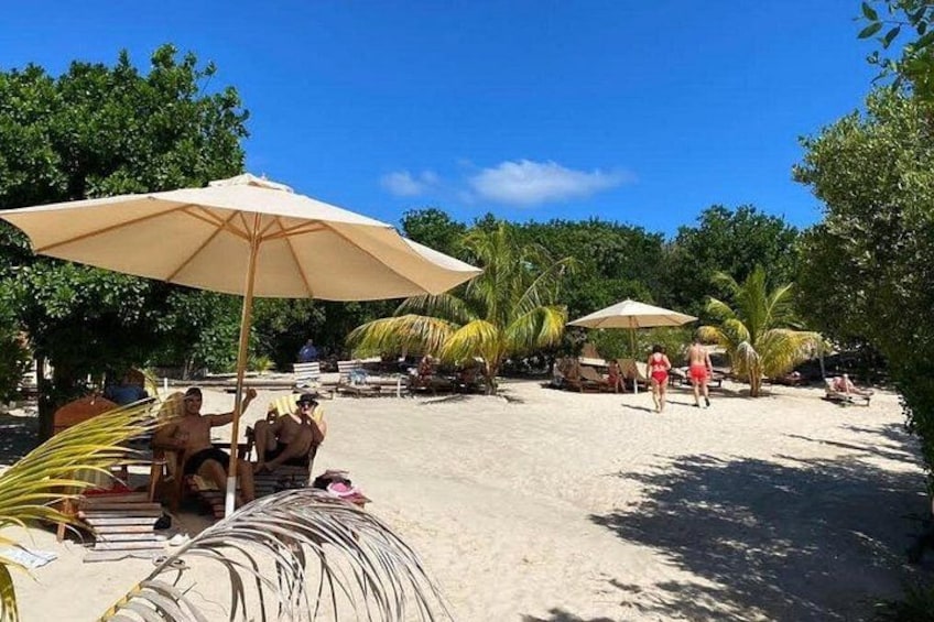 Ein Strand mit badenden Personen, Palmen und Strandsonnenschirmen. 2
