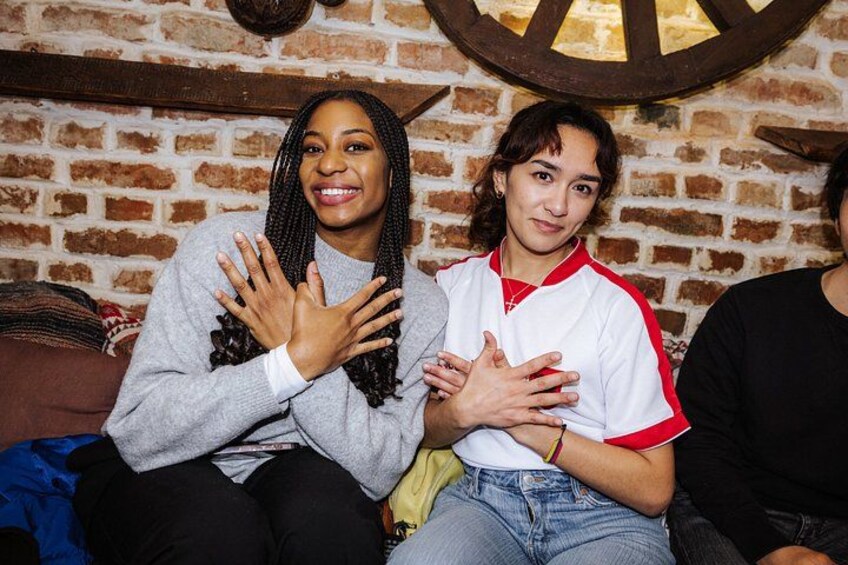 Two people sitting on a couch with a brick wall and a wooden wheel in the background. 3