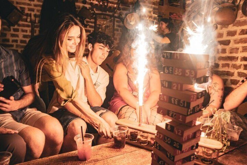 A group of people sitting around a table with a stack of numbered cards and sparklers. 3