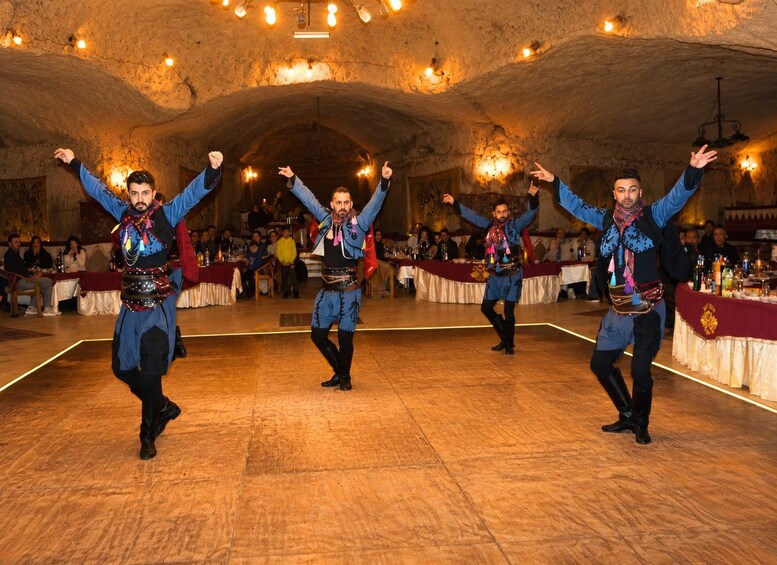 A group performing a traditional dance in a historic building with stone walls and chandeliers. 3