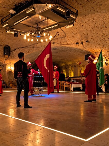 A ceremonial event with participants in traditional attire, flags, and a stage with musical instruments. 2