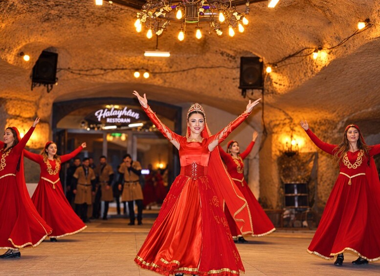 A group of dancers in red costumes performing in an indoor venue with stone walls and a chandelier. 4