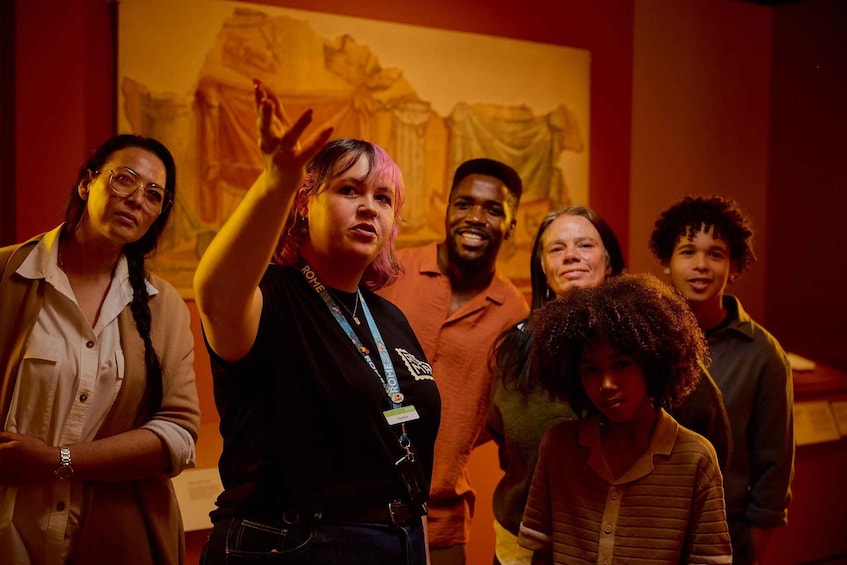A group of people in a museum with a painting in the background. 5
