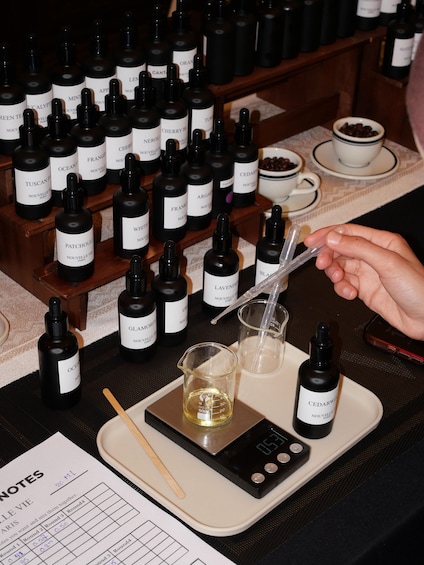 A collection of perfume bottles on a tray, a measuring device, and a cup of coffee. 4