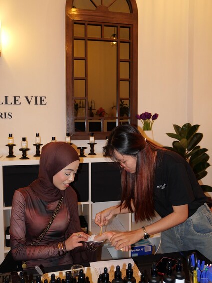 Two people at a perfume display with bottles and a mirror in the background. 3