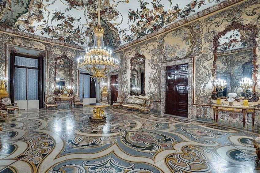 Een weelderige kamer met versierde details, een statig kroonluchter en een kamer met een patroon op de vloer. 4
