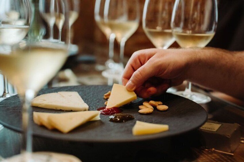 A person selecting cheese from a board with various cheeses and nuts. 2