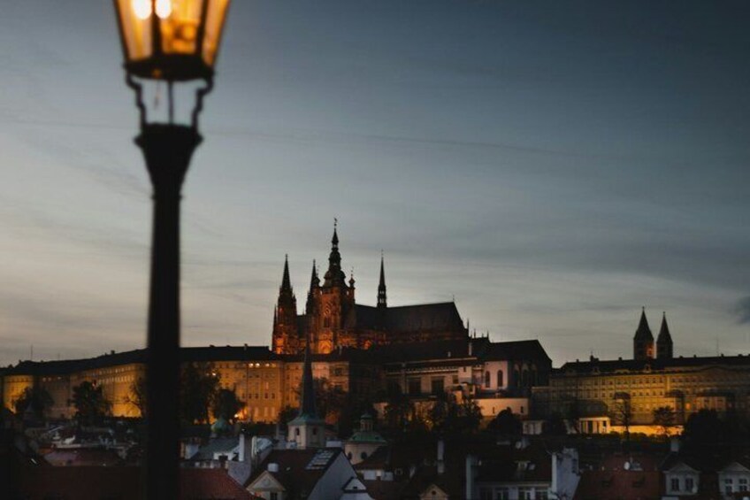 En historisk katedral med to tårne, en gadelampe i forgrunden og omkringliggende bygninger. 1
