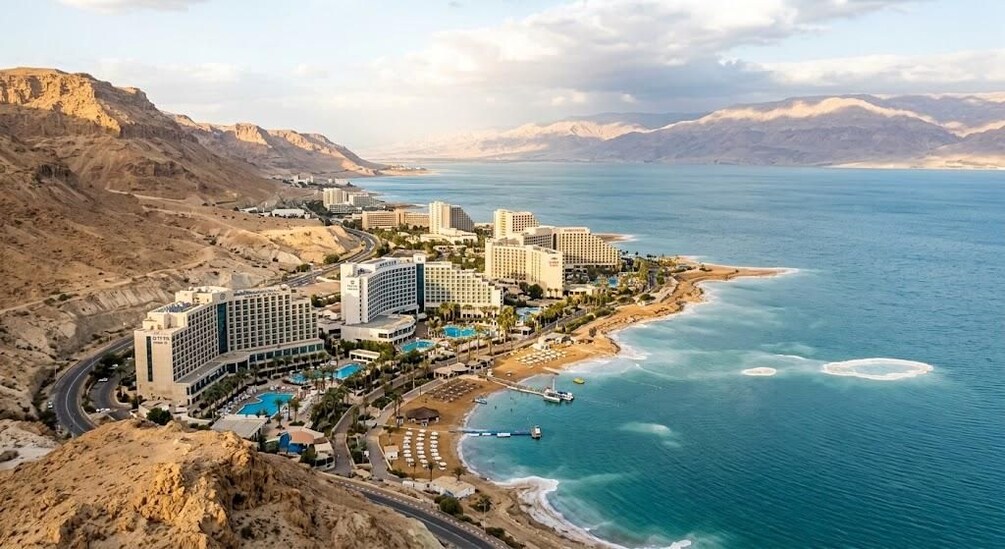 A coastal resort with hotels, a beach, and a mountainous backdrop. 2