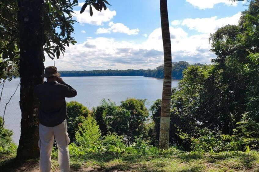 A person taking a photograph of a lake surrounded by trees. 3