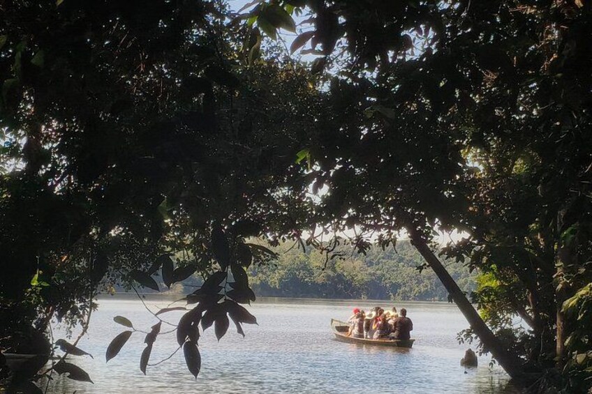 A boat with people on a calm lake surrounded by dense foliage. 5