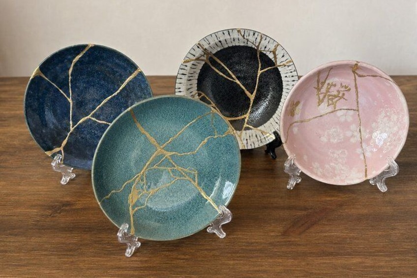 Four ceramic plates with gold crackle patterns on a wooden surface. 2