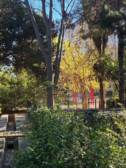 A park with trees, a wooden bench, and red poles. 3