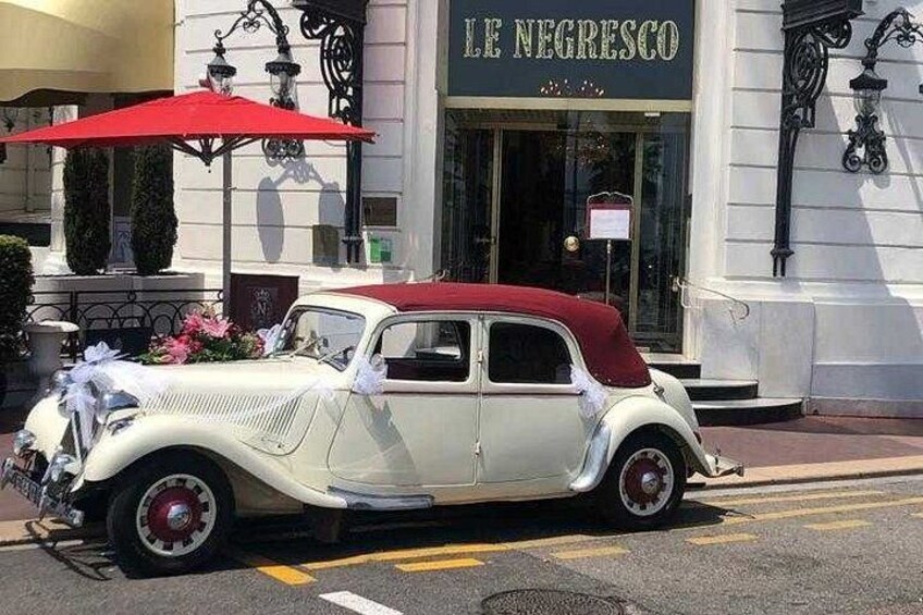En gammal bil parkerad framför en byggnad med en skylt där det står ”LE NEGRESCO”. 1