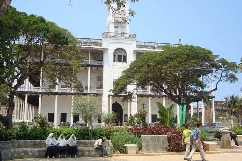 Un edificio de estilo colonial con una torre de reloj, rodeado de vegetación y un sendero pavimentado. 3