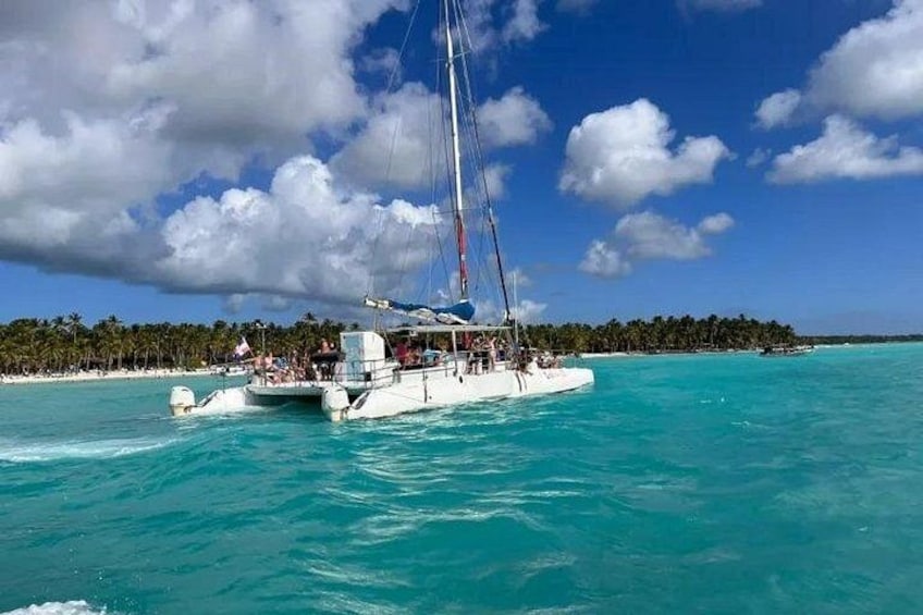 A sailboat on turquoise waters with a beach and palm trees in the background. 5