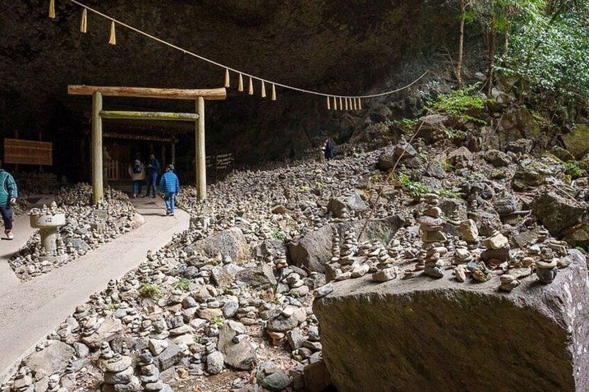A cave entrance with a wooden structure, a rocky path, and people walking. 4