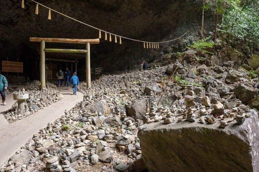 A cave entrance with a wooden structure, a rocky path, and people walking. 5