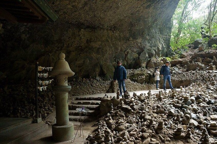 A cave with a stone lantern, a rock formation, and a group of people. 5