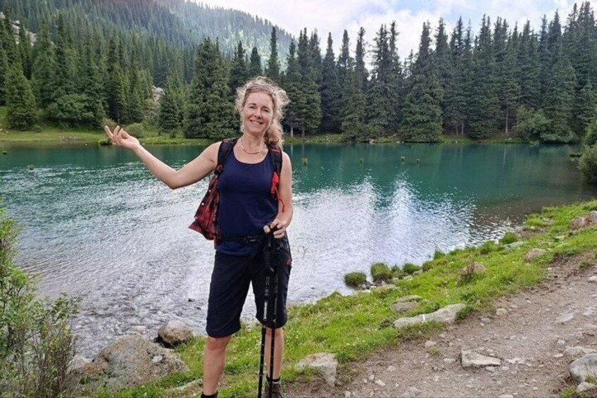 Un excursionista con mochila junto a un lago tranquilo rodeado de un bosque denso. 5