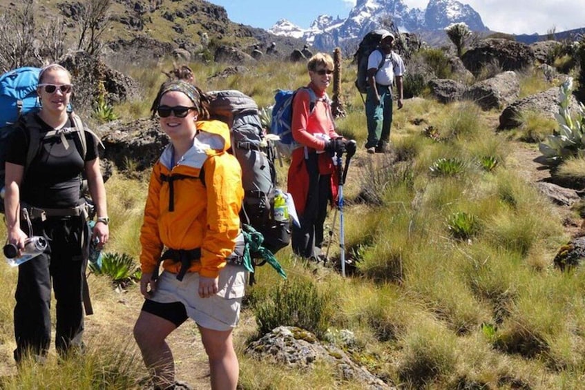 Hikers on a trail with mountainous terrain in the background. 1