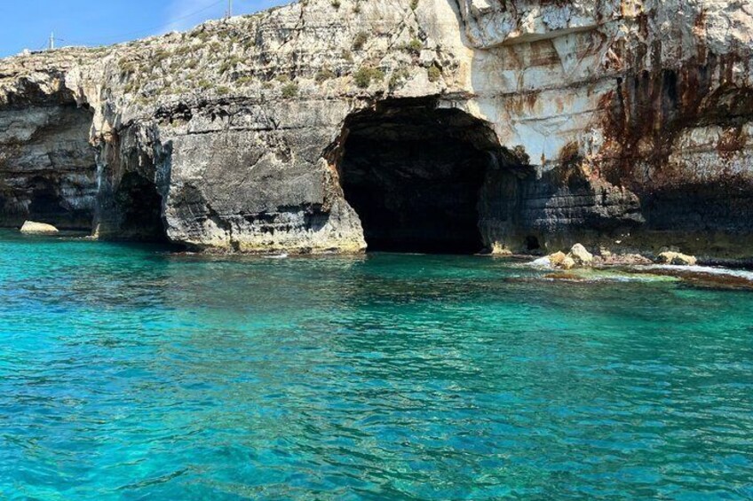A coastal cave entrance with clear turquoise water. 4