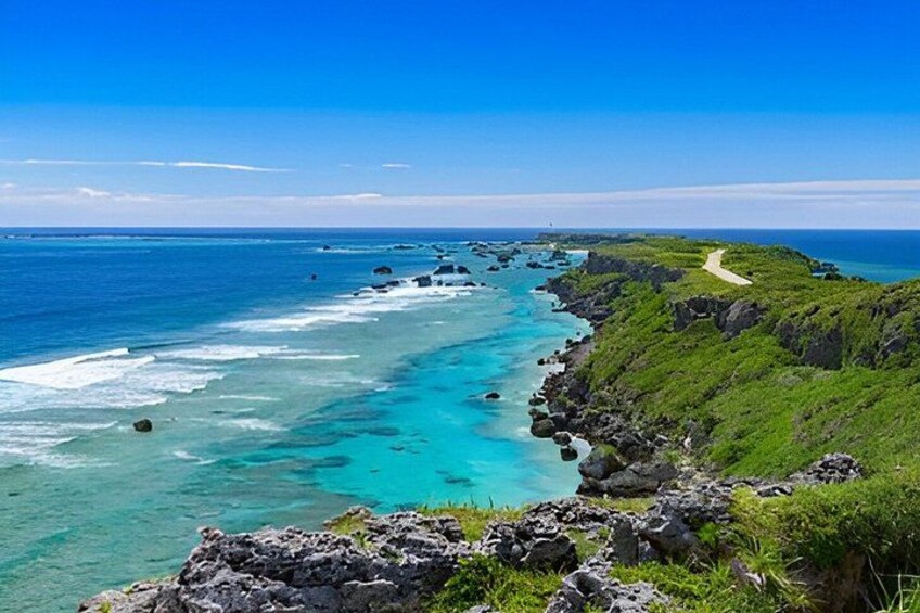 A coastal landscape with clear turquoise waters, rocky cliffs, and a winding path. 3
