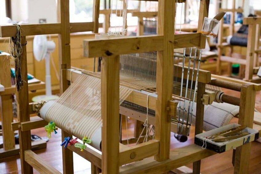 A weaving loom with a wooden frame and a fabric strip. 2