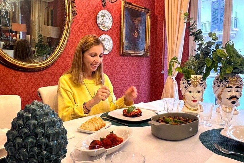 A person dining at a table with various dishes, a decorative bust, and a mirror on the wall. 4