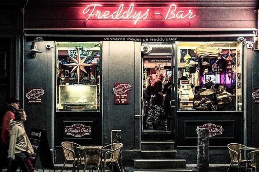 En bar som heter Freddy's Bar, med en neonskylt, en stjärndekoration och ett skyltfönster. 1