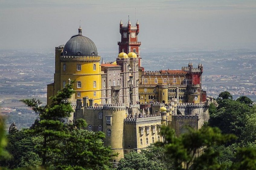 A historic castle with a prominent tower and dome, surrounded by lush greenery. 1