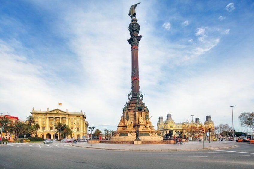 A monument with a tall column and a statue at the top, surrounded by a plaza with buildings in the background. 3