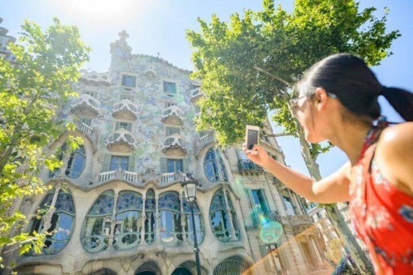 A woman taking a photo of a building with unique architecture. 2