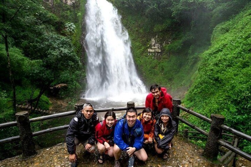 A group of people posing in front of a waterfall. 2
