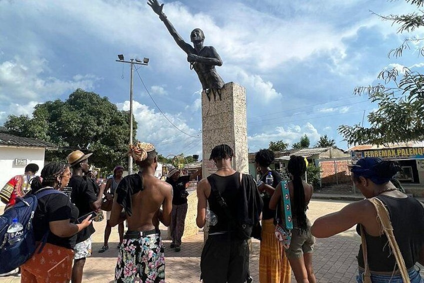 A statue of a person on a pedestal with a crowd of people around it. 5