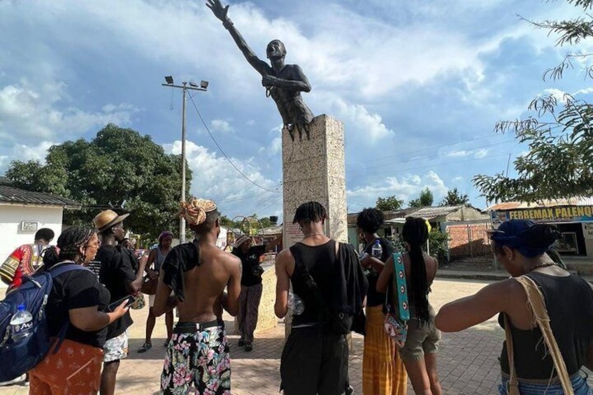A statue of a person on a pedestal with a crowd of people around it. 5
