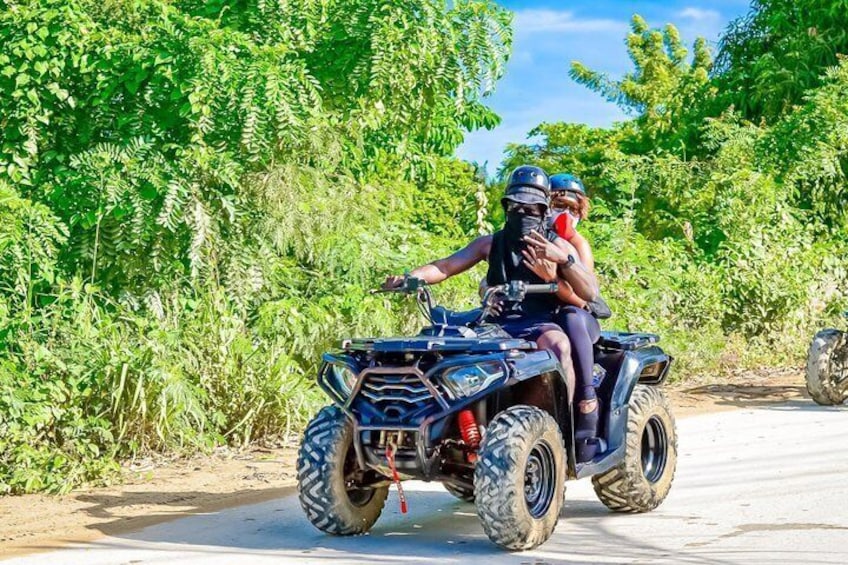 Una persona guida un quad attraverso una strada sterrata, circondata da vegetazione lussureggiante. 5