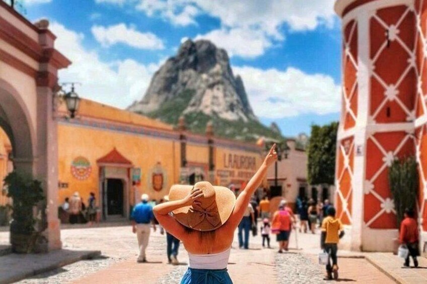 Una persona con sombrero, una montaña al fondo y un edificio con un letrero. 2