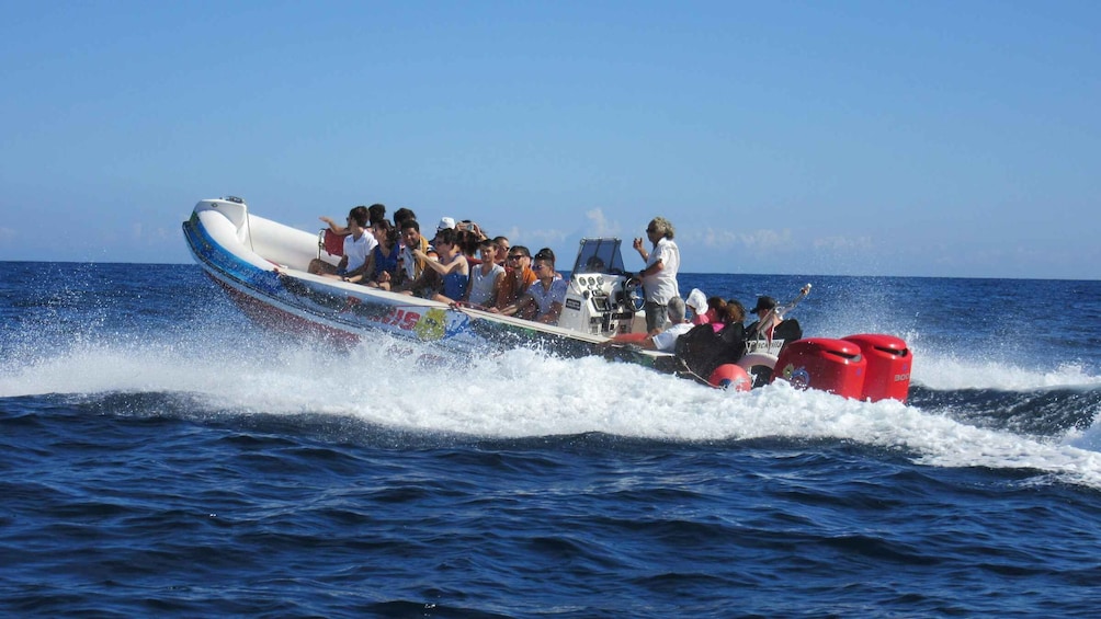 A speedboat with passengers, moving through the ocean. 1
