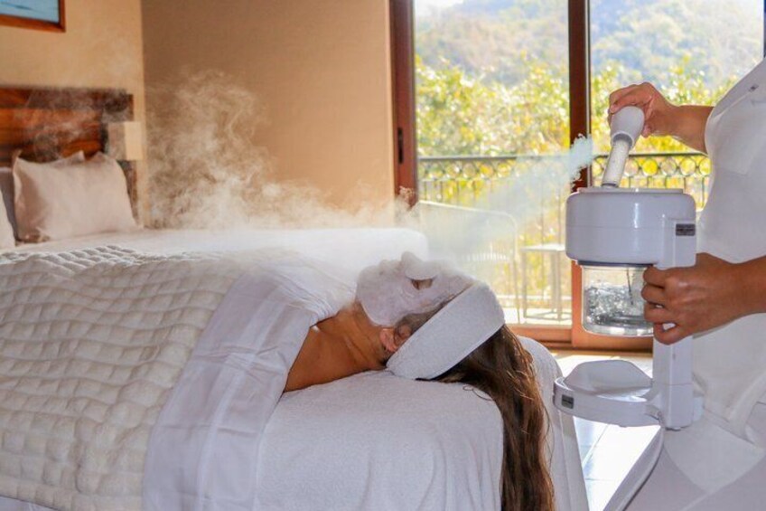 A person receiving a steam treatment in a room with a view of a mountainous landscape. 1