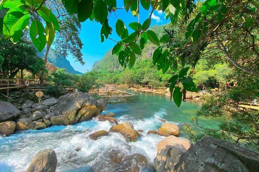A river flowing through a rocky landscape with trees and a wooden bridge. 2