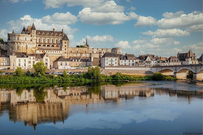 A historic town with a castle, a river reflecting the buildings, and a bridge. 1