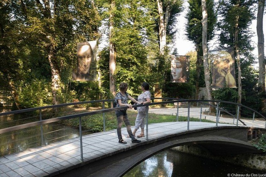 A bridge over a water body with trees and large posters. 2