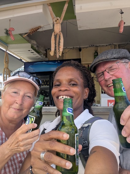 Three people holding beer bottles, a monkey decoration, and a green bottle with a label. 1