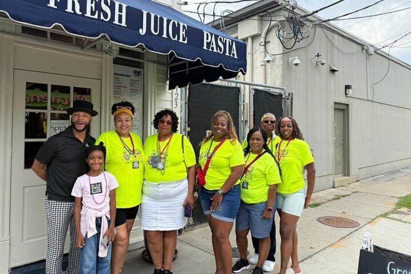 A group of people in front of a building with a sign that reads 'FRESH JUICE PASTA'. 5