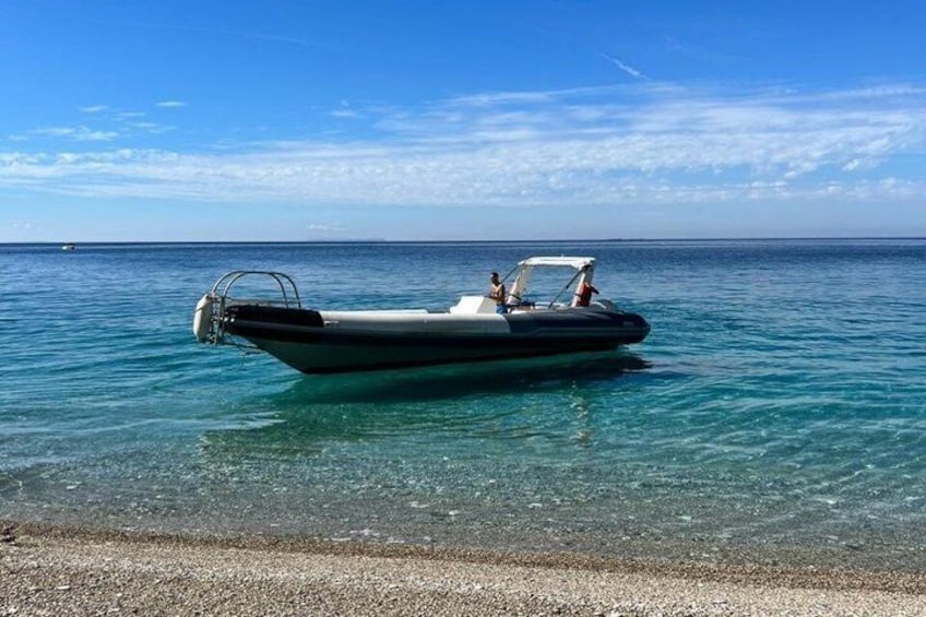 Una pequeña lancha en aguas turquesas tranquilas cerca de una playa de guijarros. 4